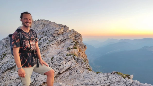 Bild på Michael Baumgärtner i halvfigur, stående på en stenig bergstopp