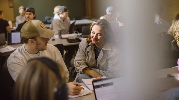 Nöjda studenter pratar med varandra i ett klassrum.